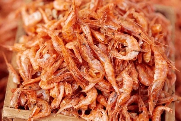 Close-up of vibrant orange dried crayfish piled in a wooden tray for Nigerian soups and stews